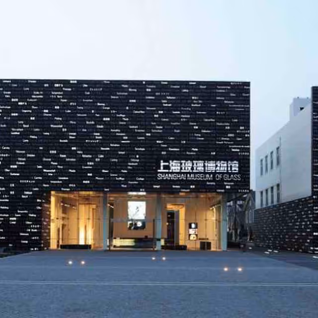 Exterior of the Shanghai Museum of Glass with a black facade featuring numerous small illuminated words and a large glass entrance.