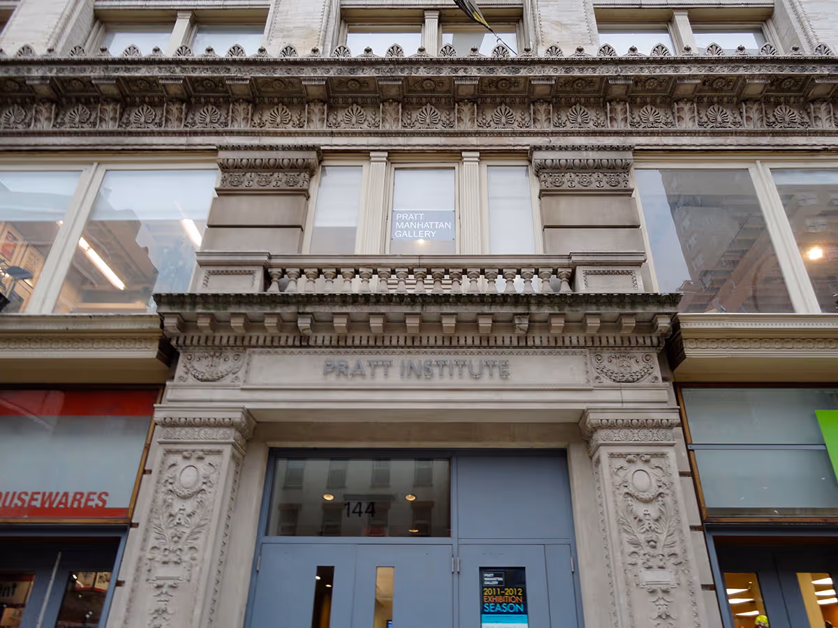 Ornate entrance of the Pratt Institute building with carved stone details and glass doors labeled 144.