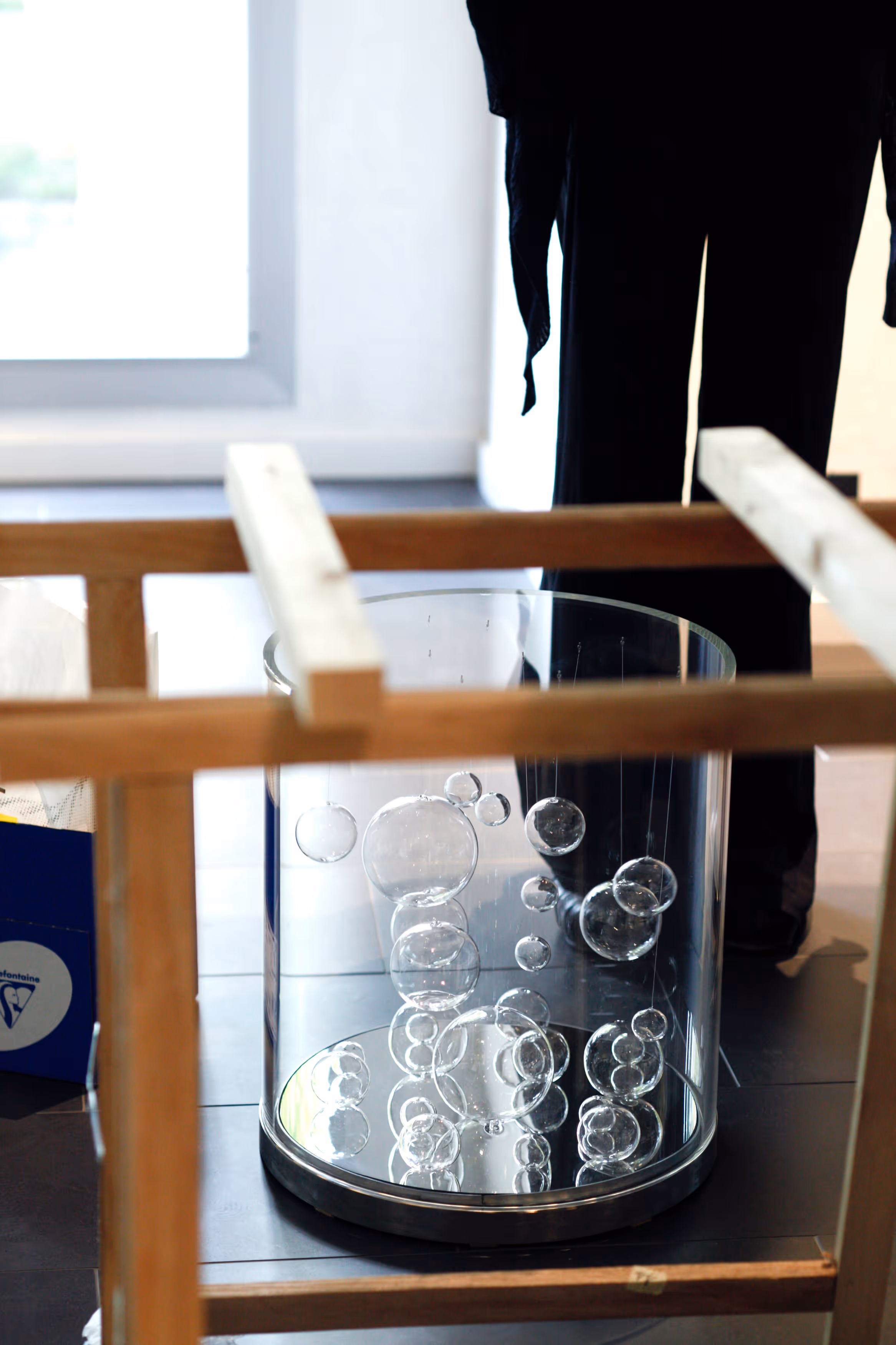 Transparent cylindrical display case containing various sizes of clear glass bubbles inside.