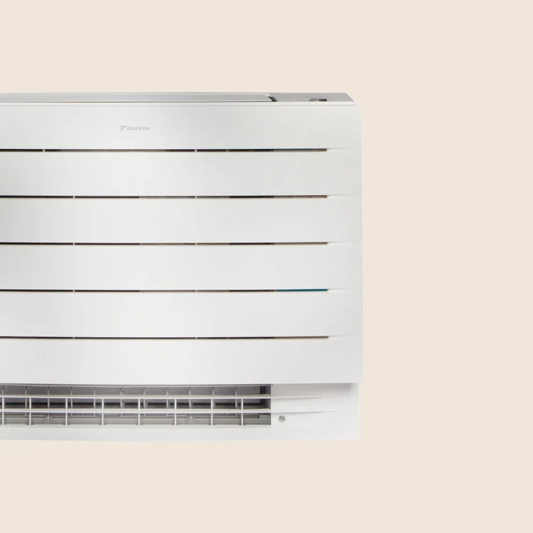 Unité murale blanche de climatisation Daikin contre un mur beige.