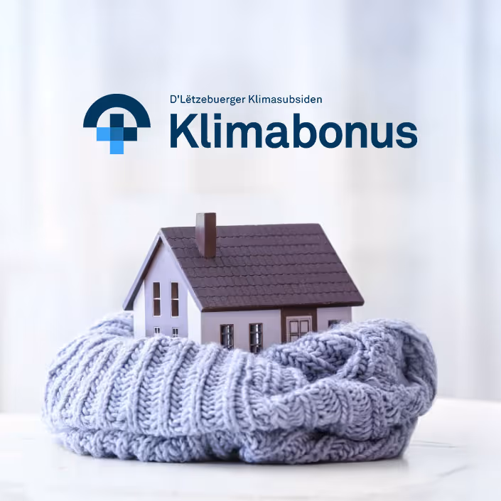 Logo Klimabonus au-dessus d'une maison miniature enveloppée dans une écharpe tricotée, symbolisant l'isolation thermique.