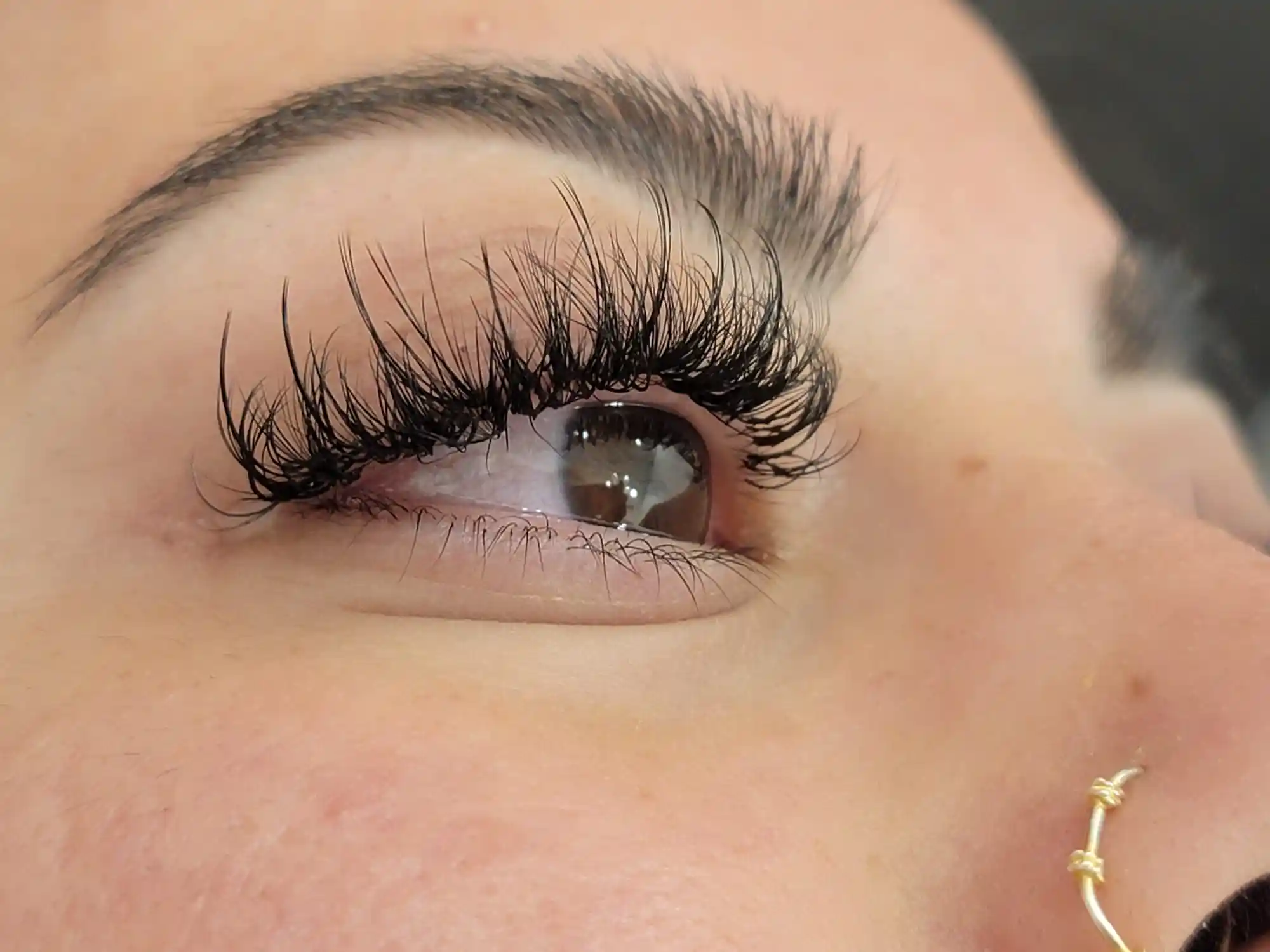 Close up of volume lash extensions on brown eye with layered length and fluffy texture