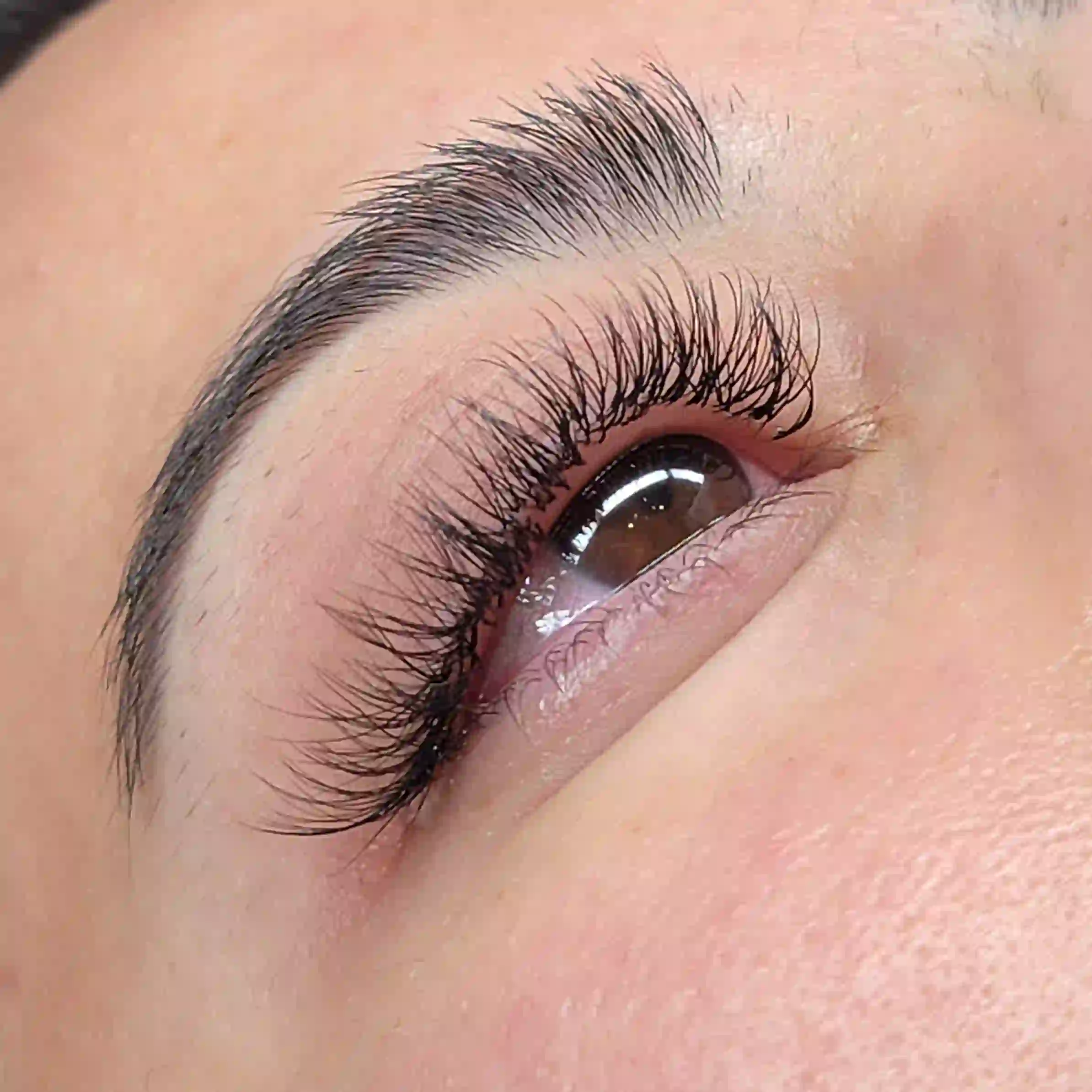 Close up of volume lash extensions on brown eye with dramatic length and soft texture, luxury mobile lash service by Opalya