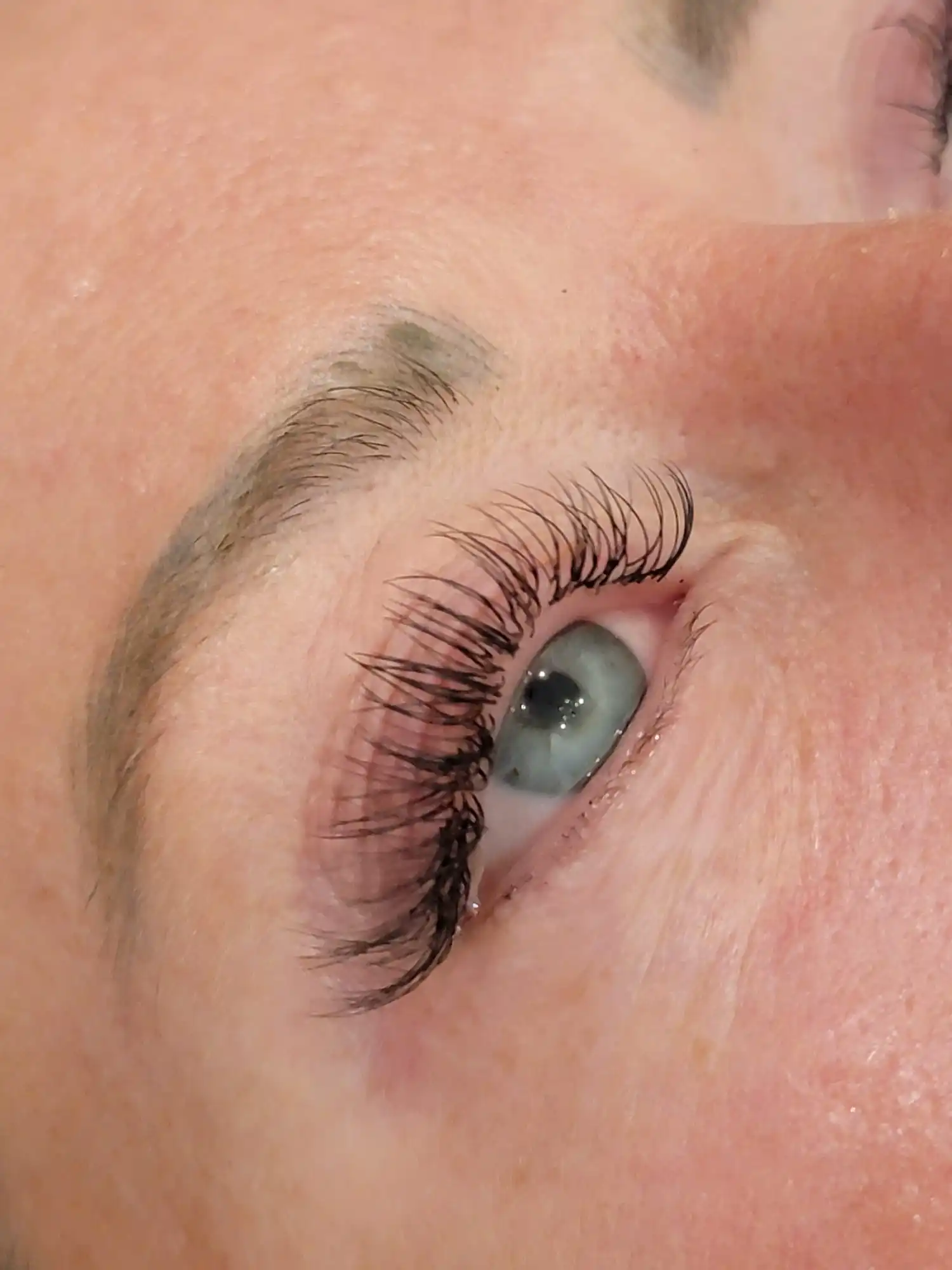 Side view of classic lash extensions on light colored eye with soft lift and defined lash line
