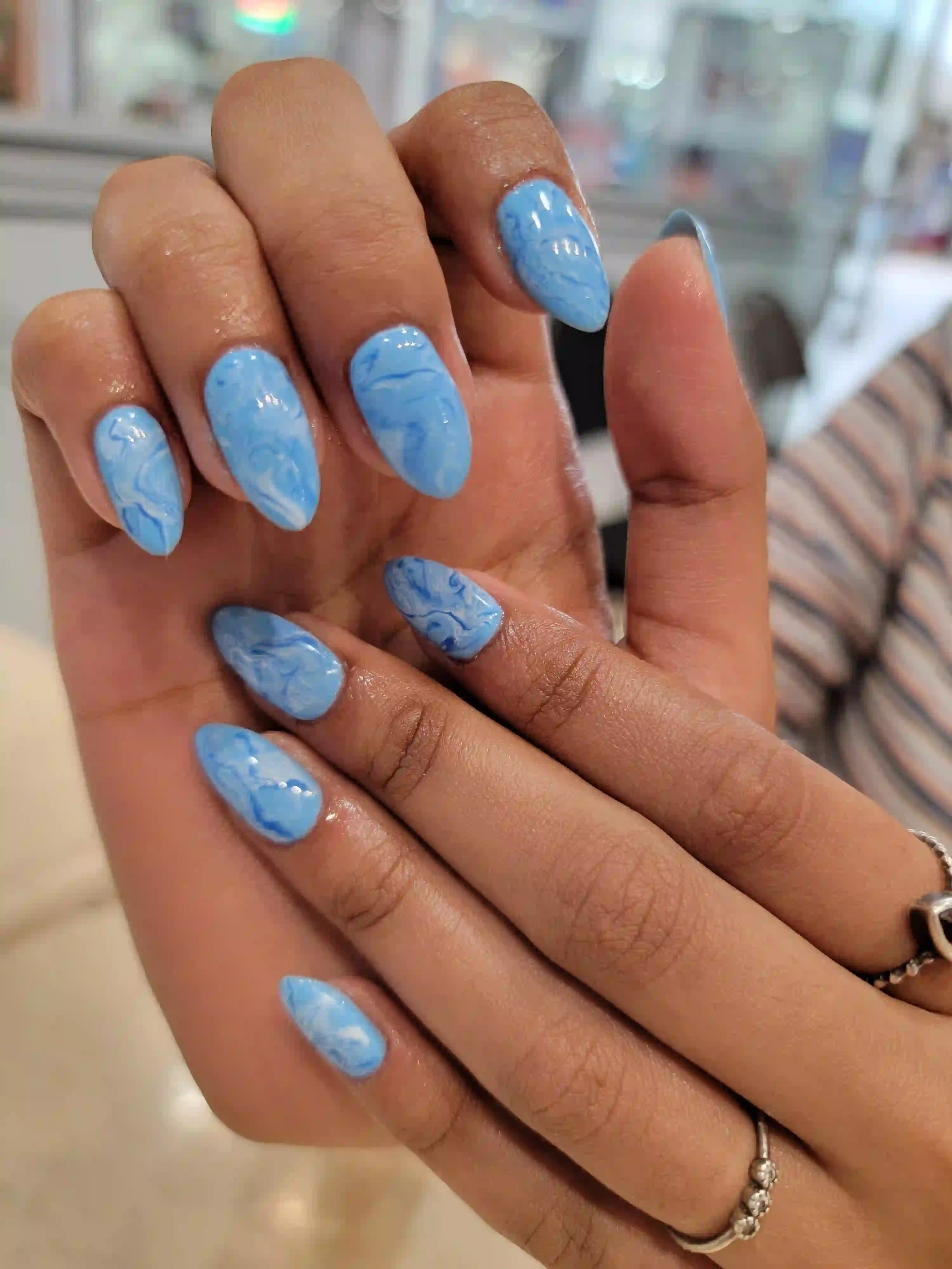 Light blue marble gel manicure on almond shaped nails with glossy finish, professional mobile nail service by Opalya in Toronto