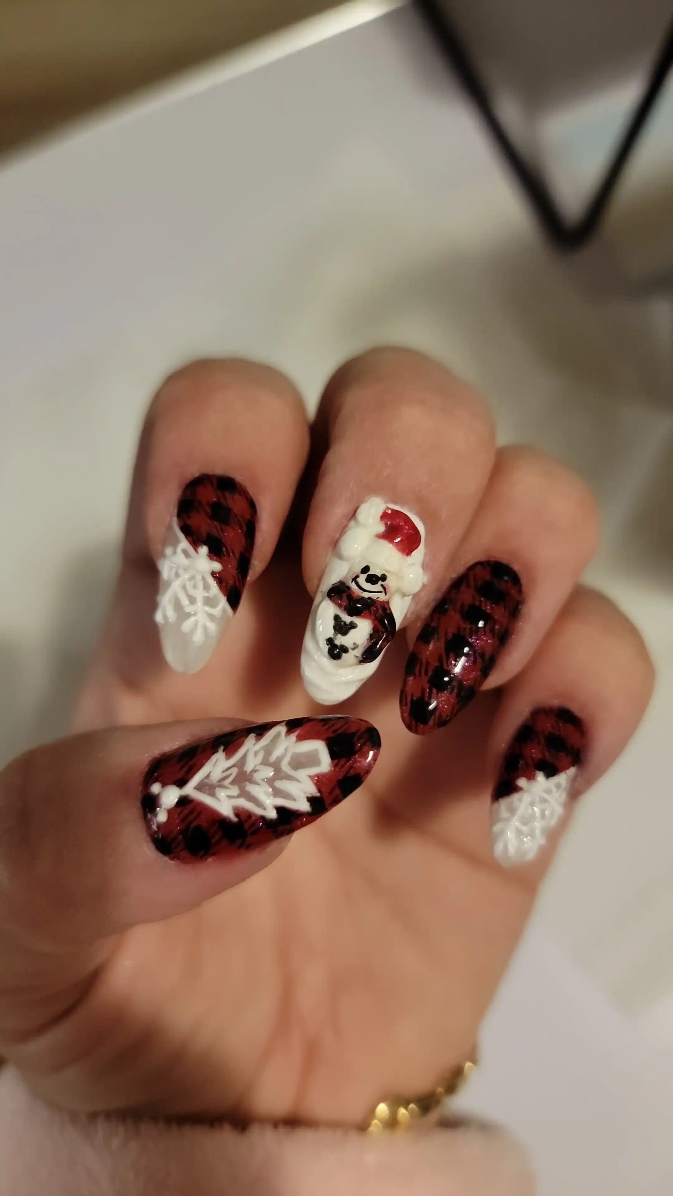 Red and black plaid nail art with white snowflake accents and 3D holiday details, festive winter manicure by Opalya mobile spa