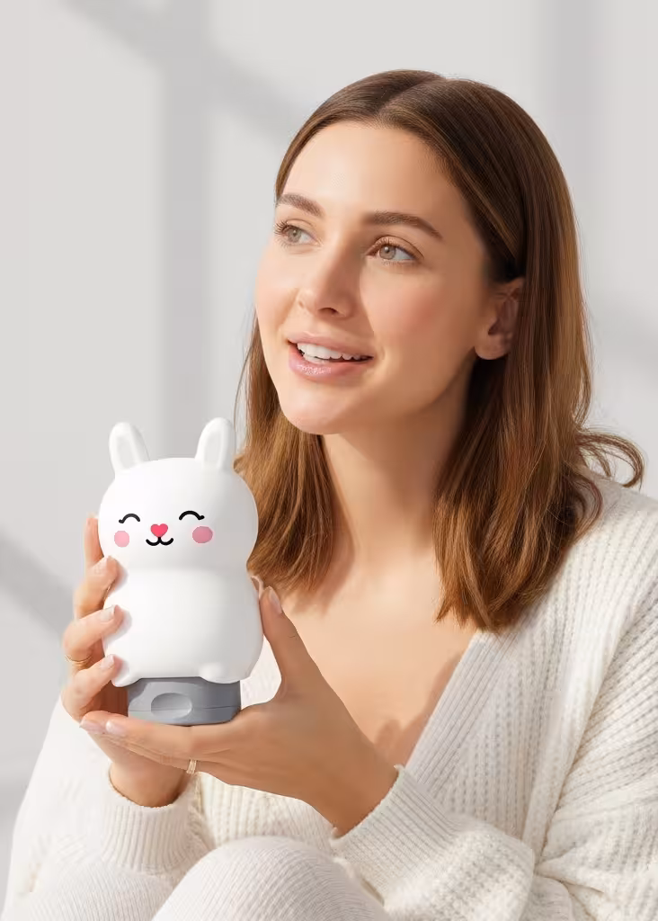 Smiling mom holding Milky Care bunny-shaped shampoo bottle in soft daylight, expressing trust and happiness with gentle kids’ formula