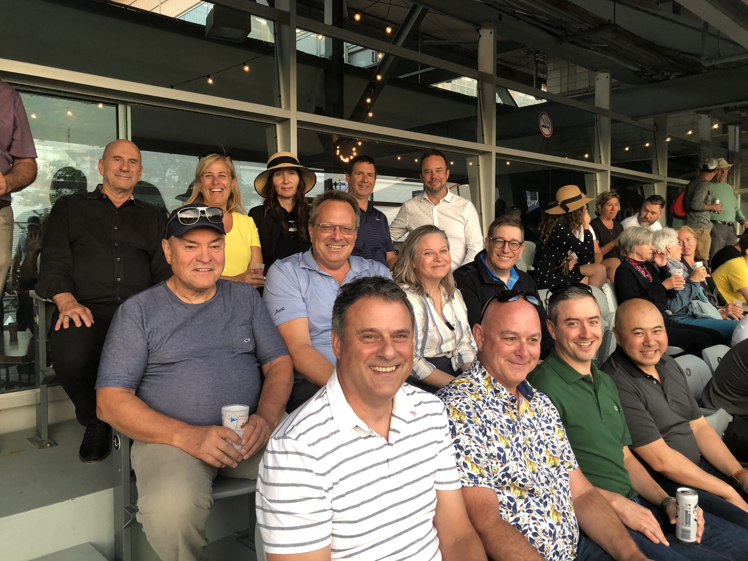 Group of smiling people at indoor event with string lights and drinks