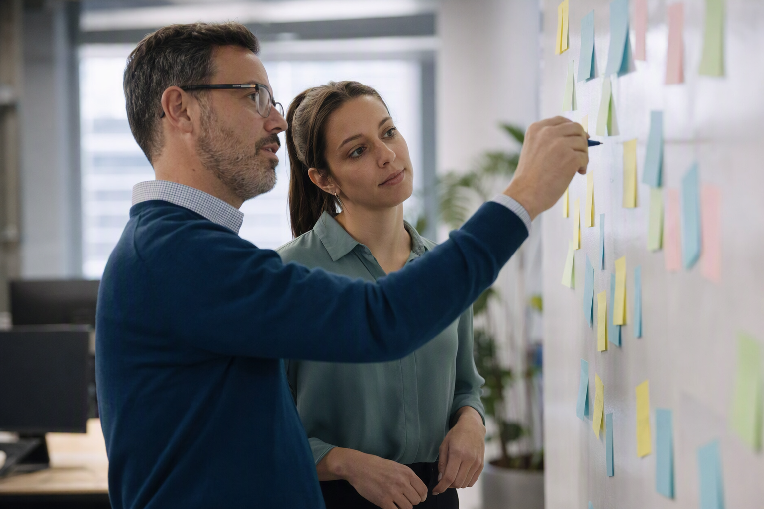 Gestionnaire et analyste cartographiant un processus hebdomadaire sur un mur de notes autocollantes dans un bureau québécois