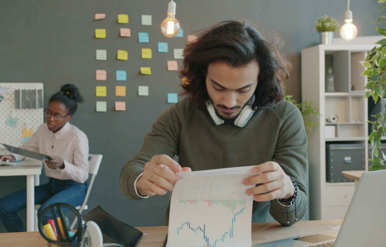 Colleagues discussing graphs and documents in an office.