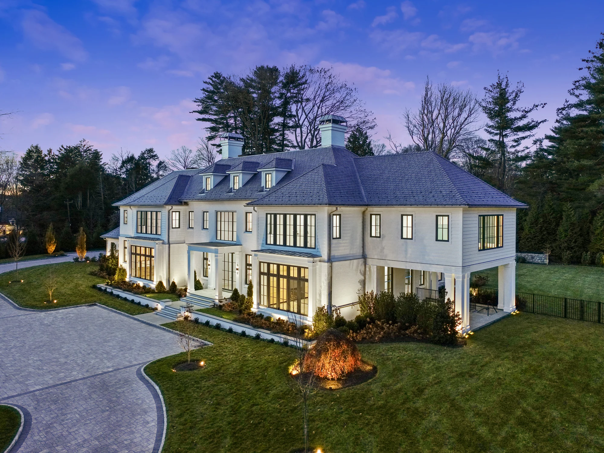 Modern house with large glass windows at dusk.