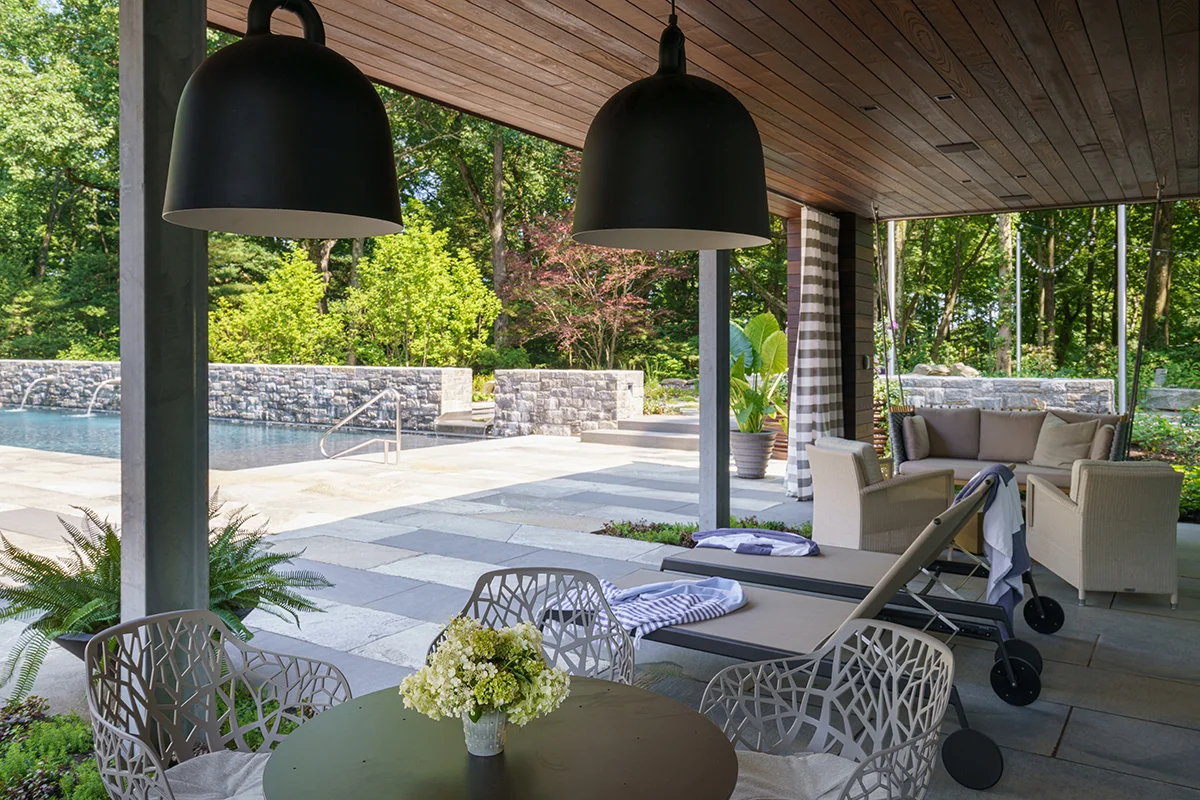 Covered outdoor patio with pool, lounge seating, and pendant lights.
