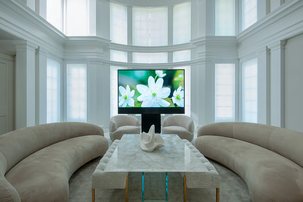 Living room with curved sofas and TV in bay window alcove.
