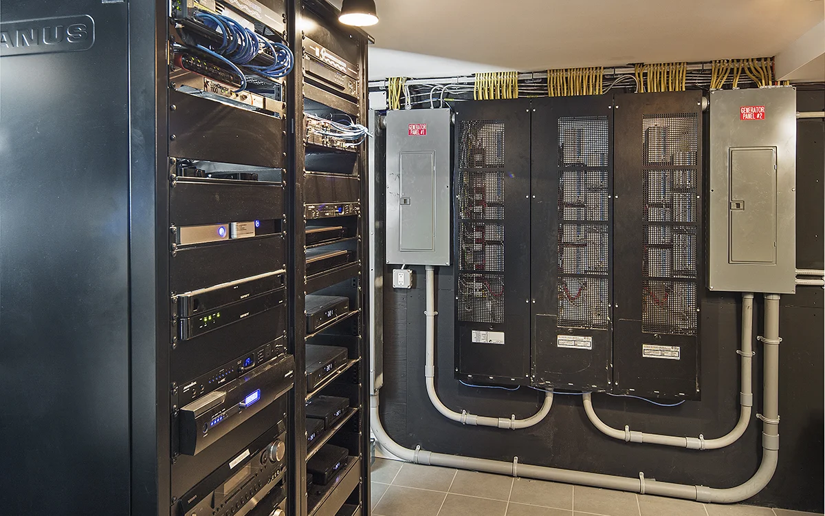 Server rack and electrical panels in utility room.