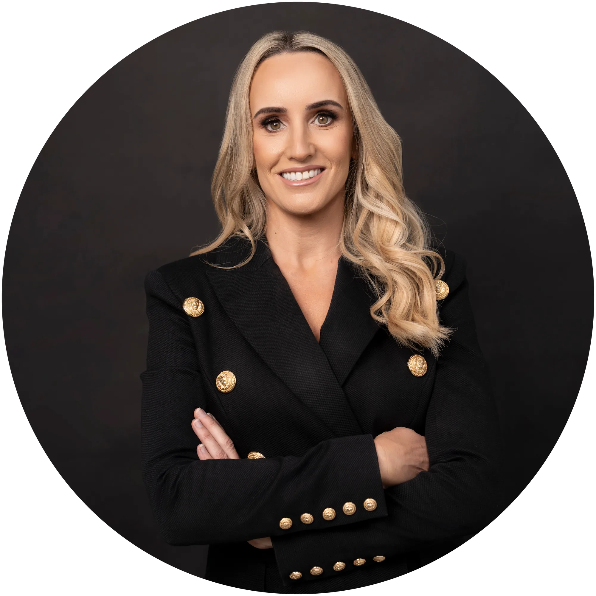 Smiling woman with long blonde hair wearing a black blazer with gold buttons against dark background.