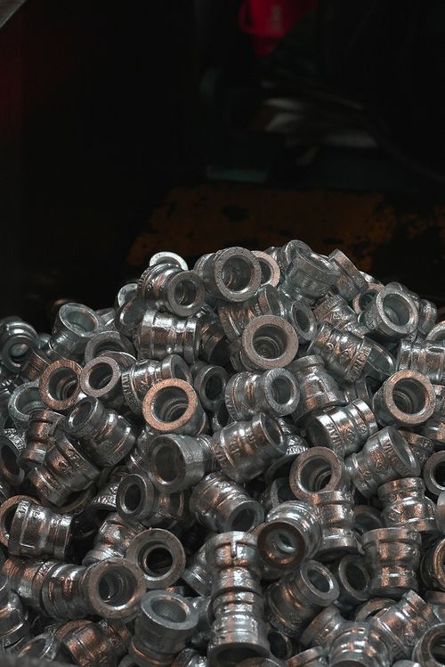 Pile of small metallic cylindrical parts with hollow centers stacked together.