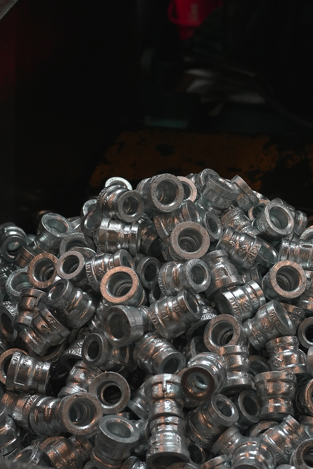 Pile of small metallic cylindrical parts with hollow centers stacked together.