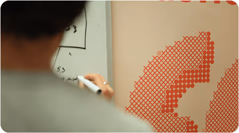 A person writing on a white board in Agemo's office