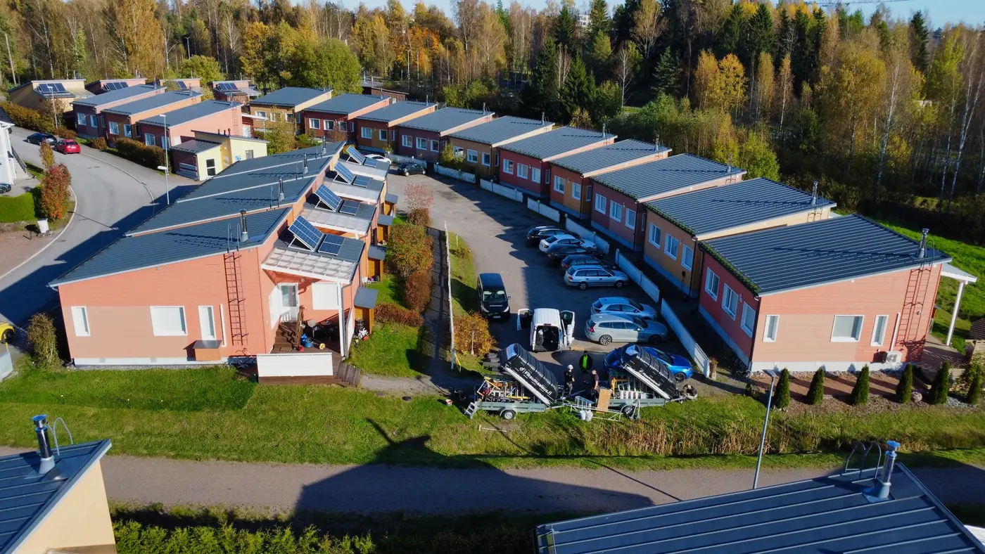 Fiksumaalauksen työmaa rivitaloyhtiössä ilmakuvassa, kalusto ja peräkärryt pihalla