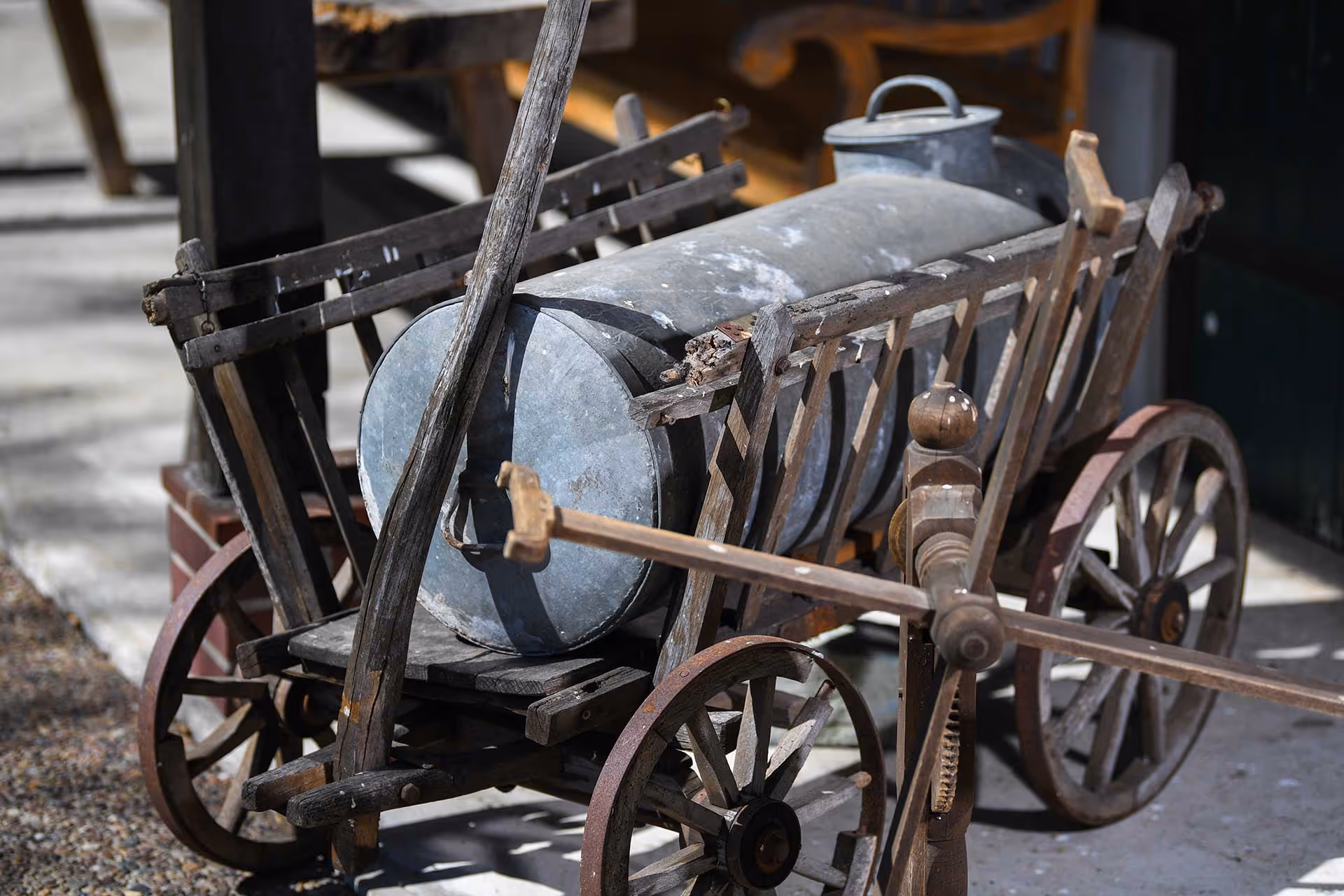 Ein Milchfass in einem Holzwagen liegend.