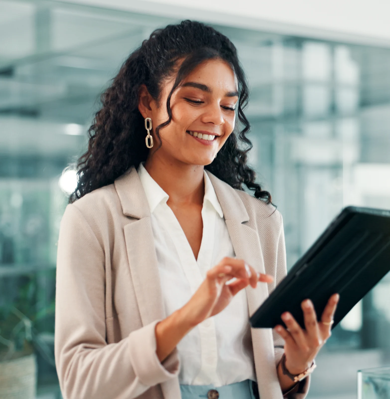 Lächelnde Frau mit lockigem Haar, die eine digitale Tablette in einem modernen Büro verwendet.