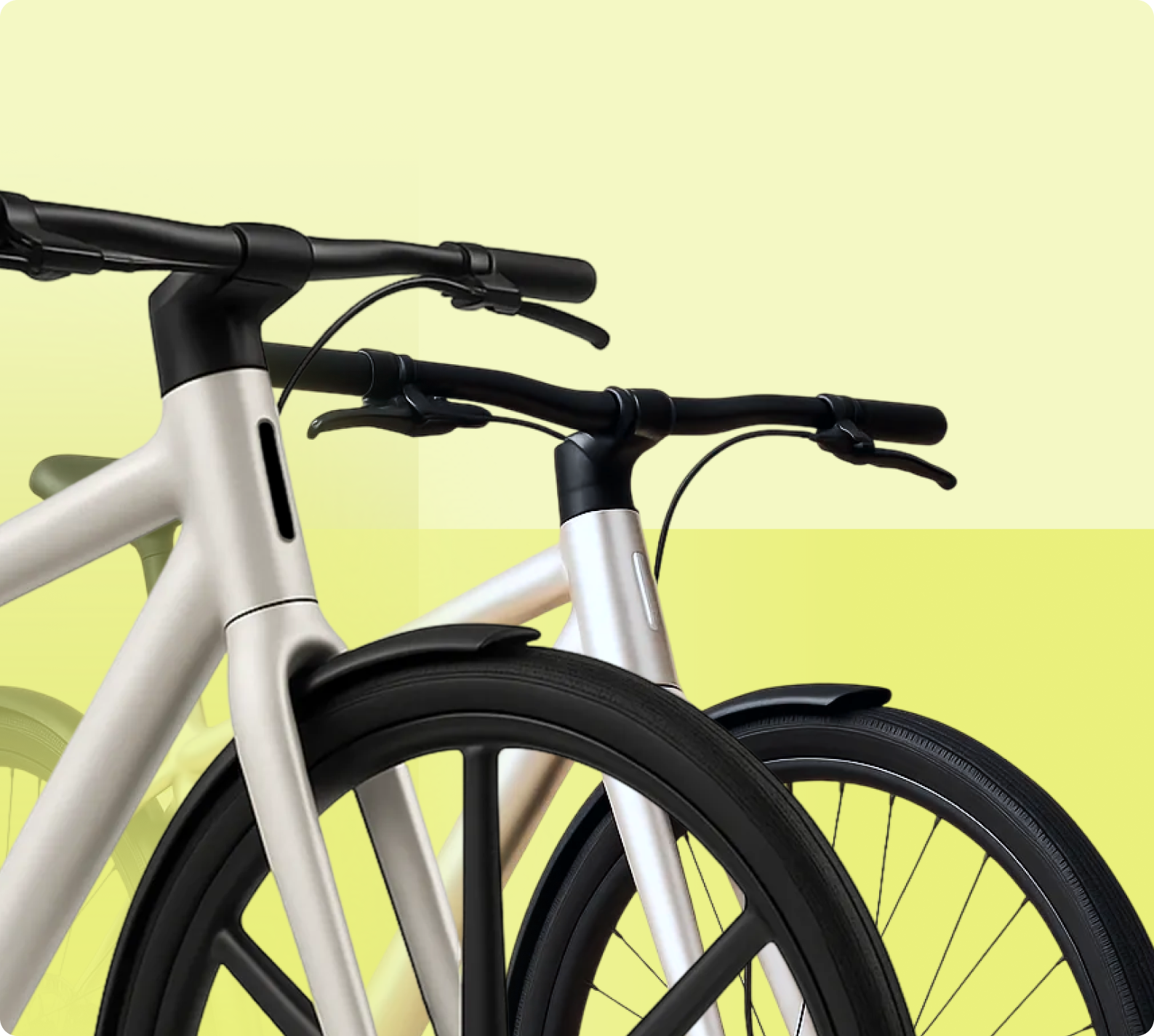 Nahaufnahme von zwei modernen Fahrrädern mit weißen Rahmen und schwarzen Lenkergriffen vor gelbem Hintergrund.