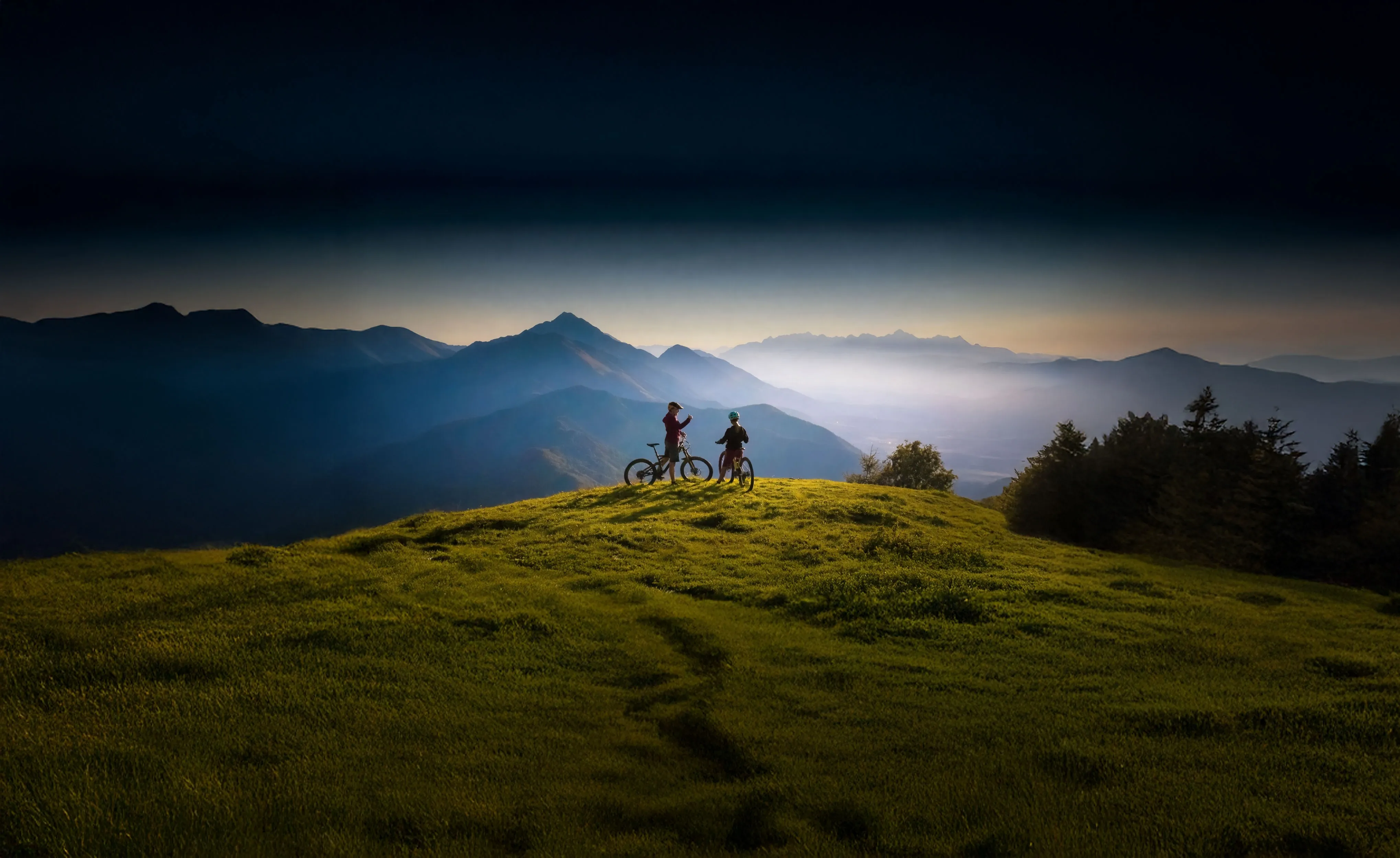 Two people on a mountain top with bikes.