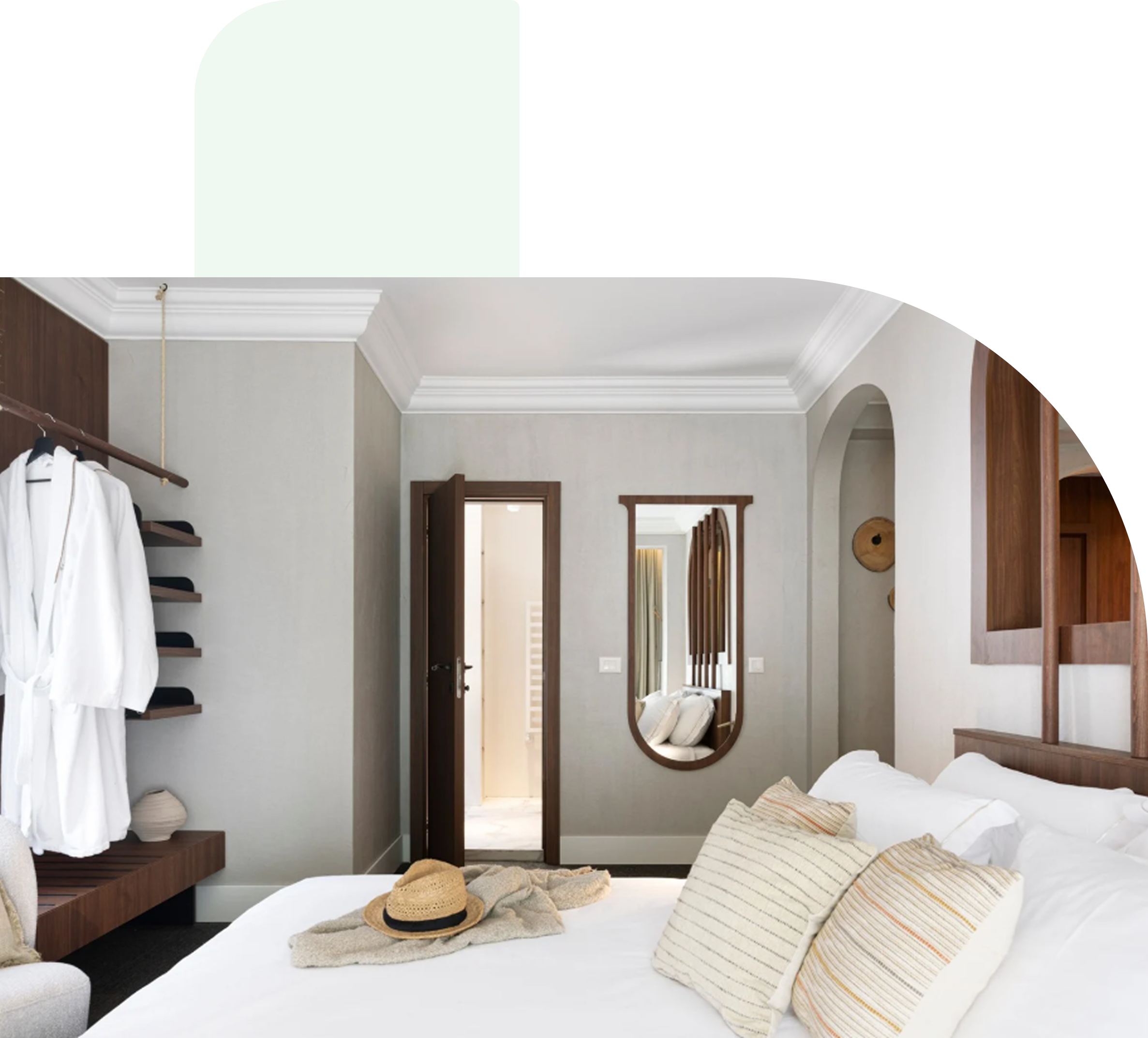 Hotel reception area with green velvet chairs and a couple with luggage checking in, two receptionists behind the counter, and a staff member holding a clipboard.