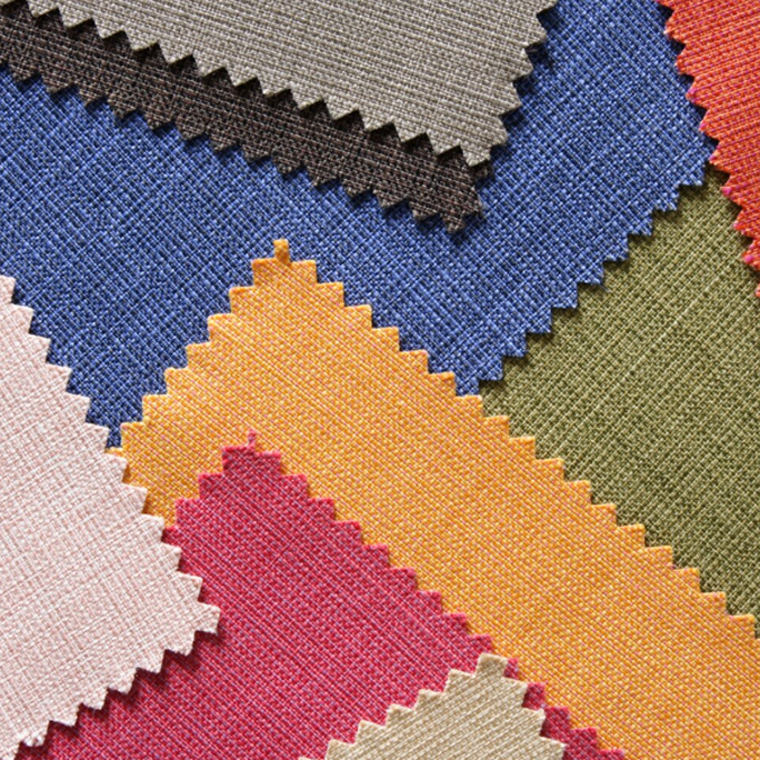 Close-up of overlapping fabric swatches with zigzag edges in colors blue, orange, red, green, beige, brown, and pink.