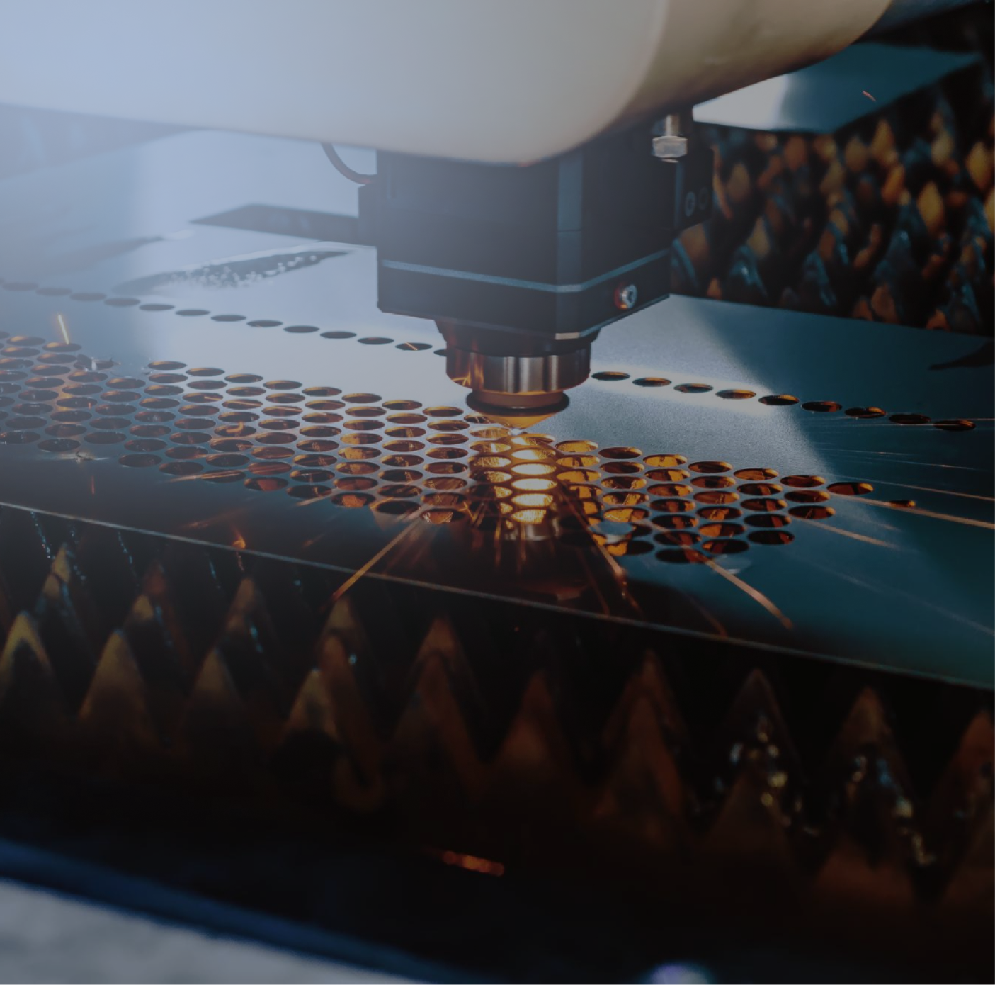 Close-up of a laser cutting machine engraving circular holes into a metal sheet.