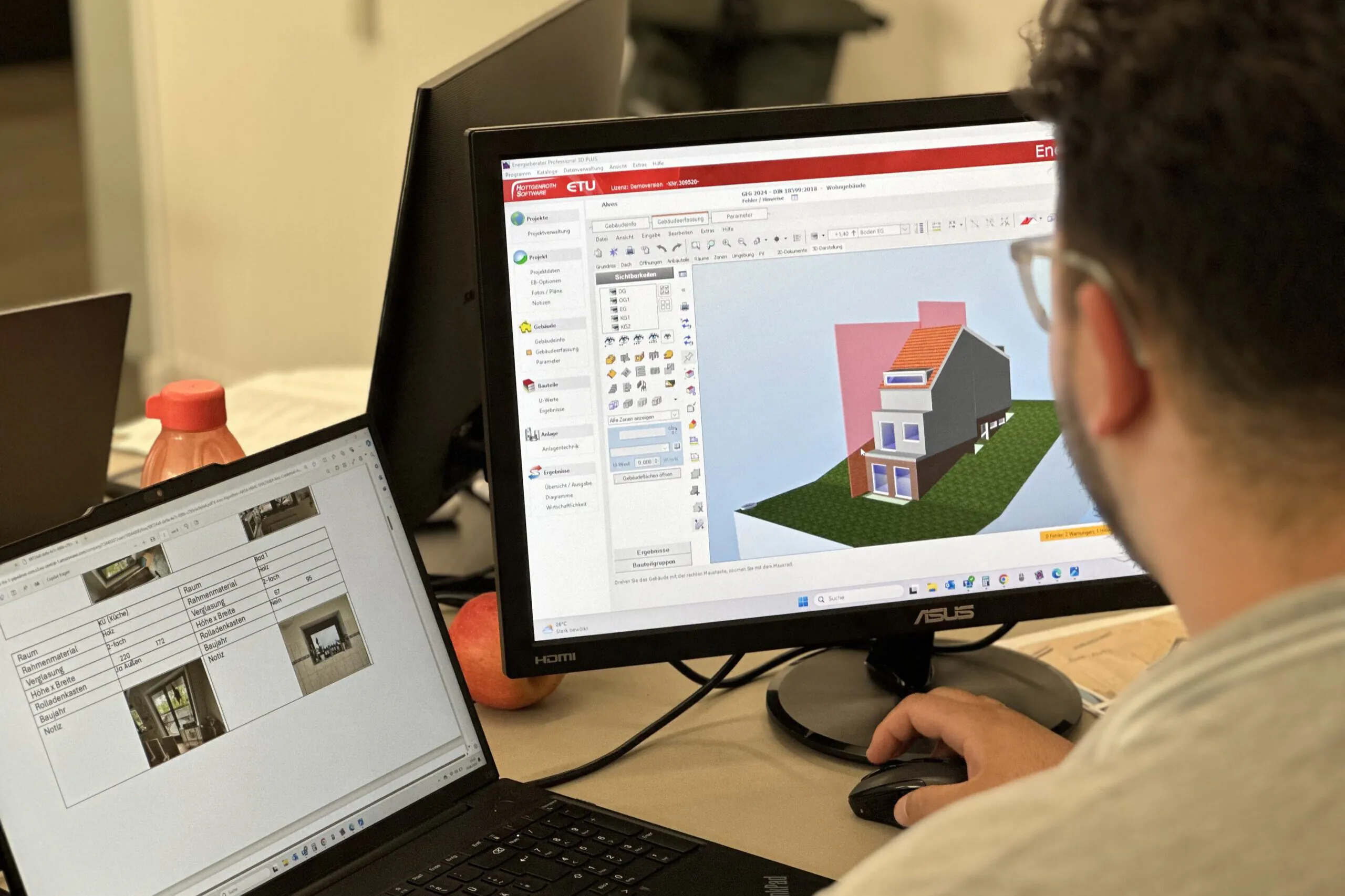 Person arbeitet am Computer mit einer 3D-Hausmodell-Software, daneben Laptop mit Tabellen und Bildern von Fensterdaten.