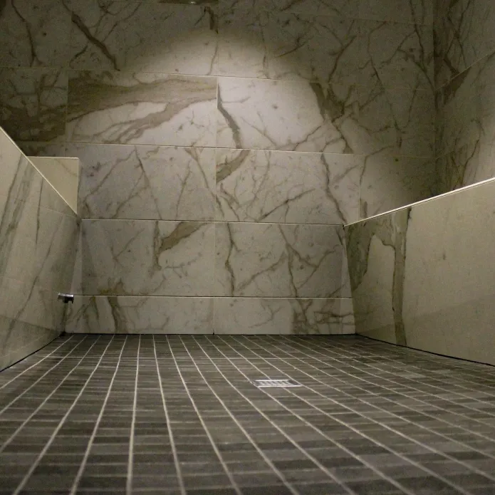 Intérieur de sauna moderne avec murs carrelés en marbre et banquettes en bois.