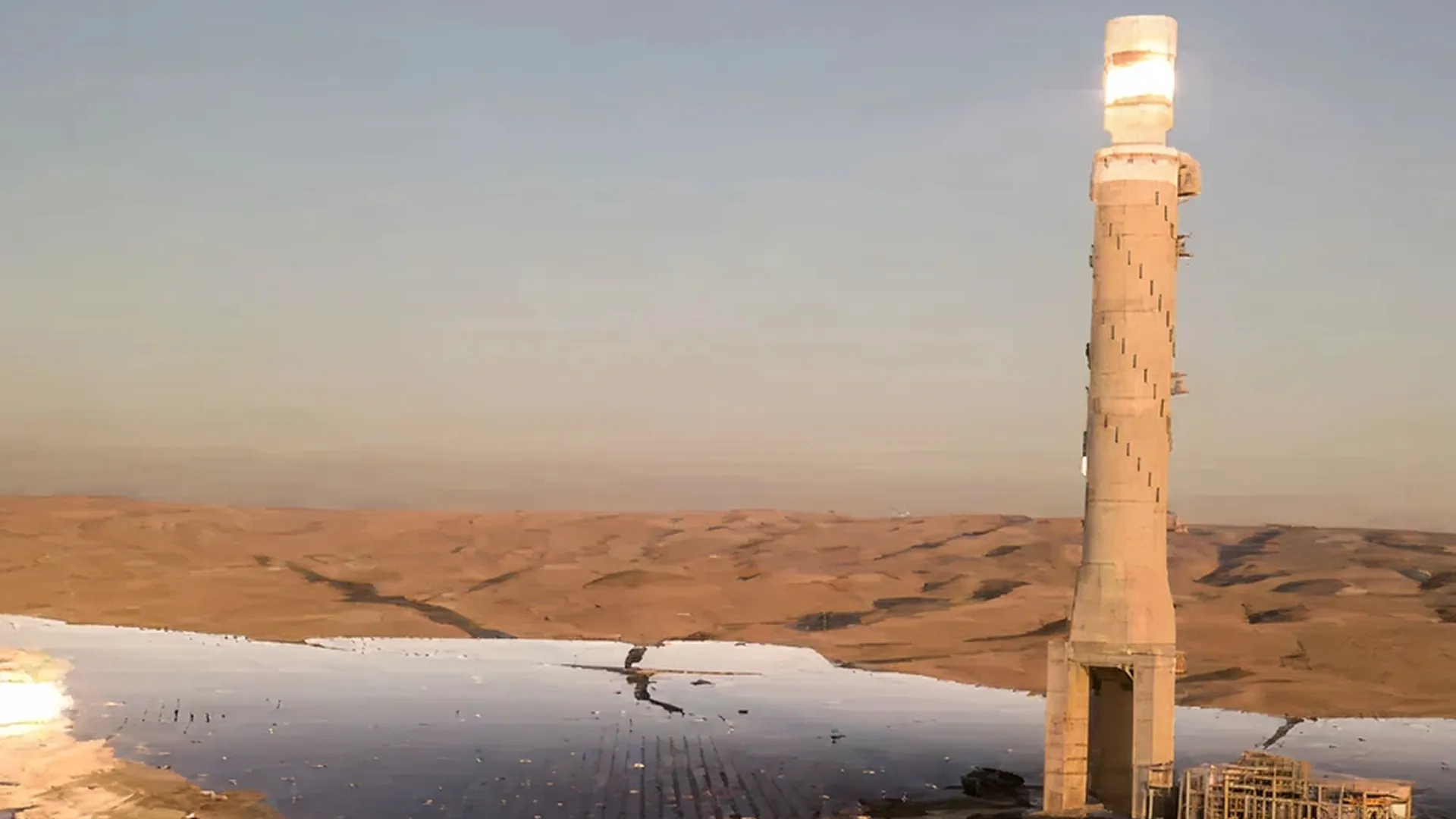 Solar tower in a desert with mirrors that reflect light to a central point at the top of the tower.