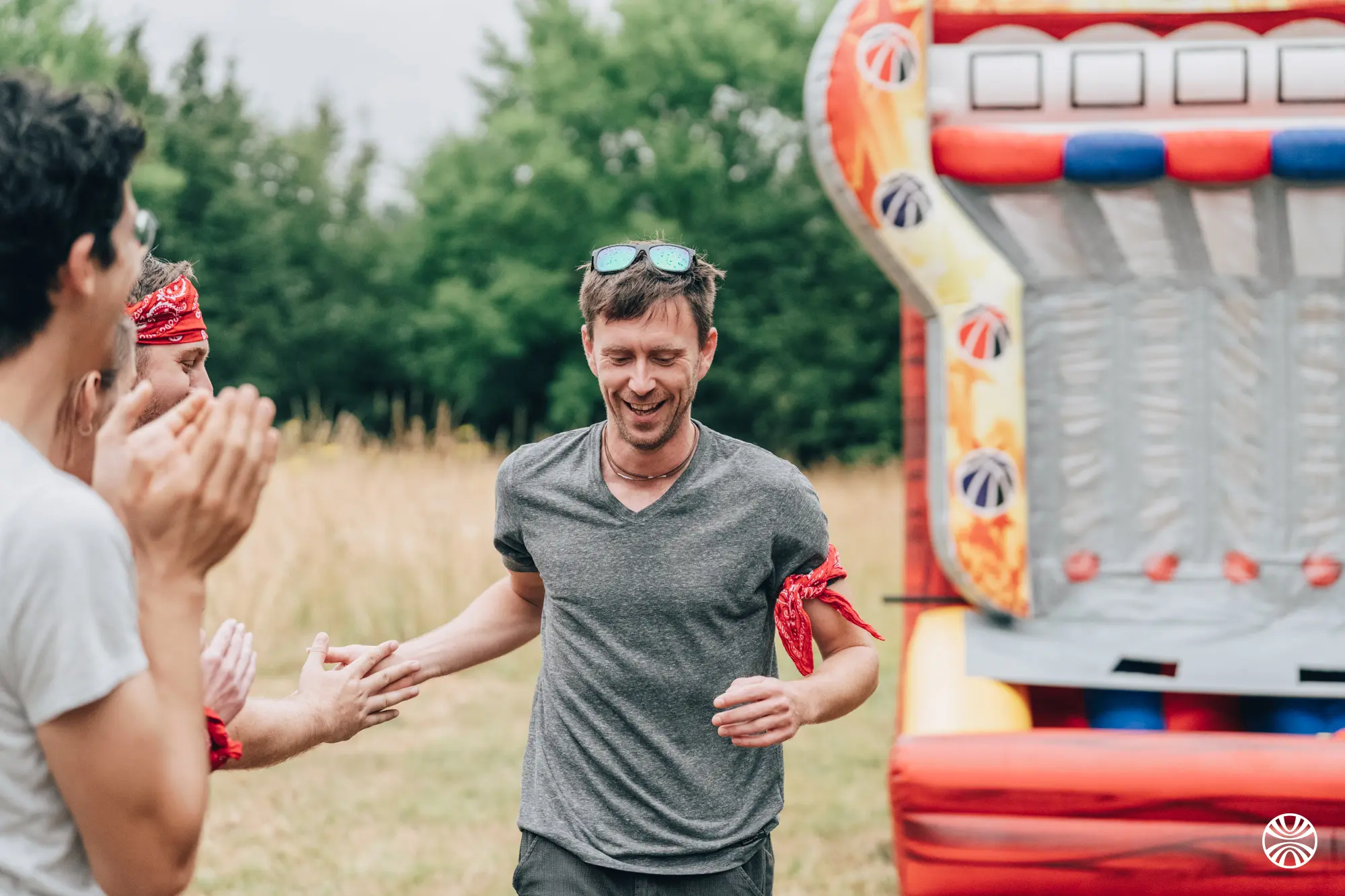 Deux hommes discutent sérieusement dans une salle avec des tables et chaises en bois, tandis que d'autres personnes sont assises en arrière-plan.