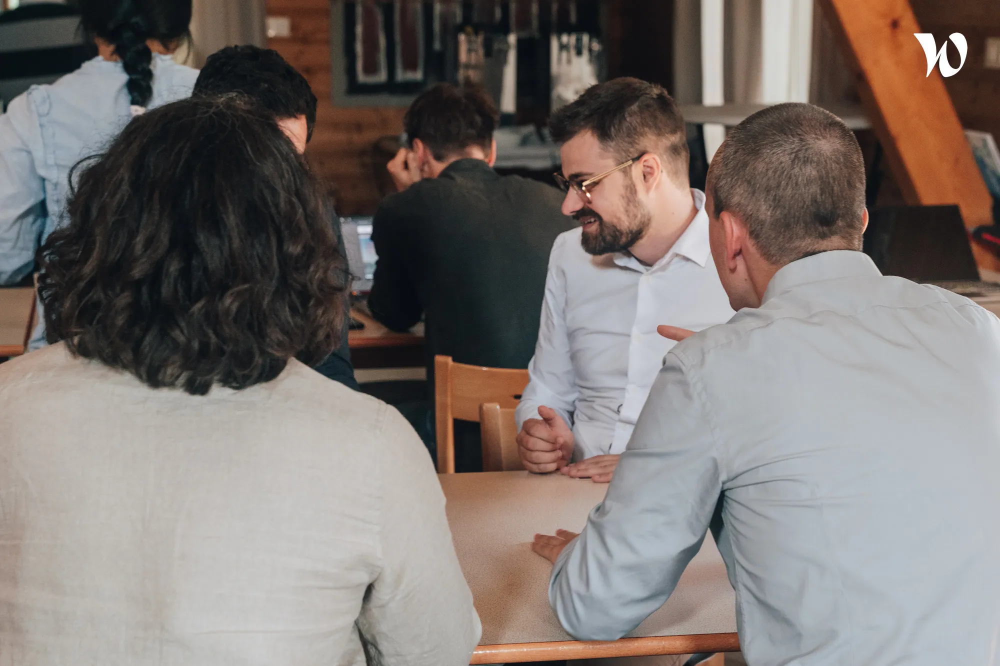 Quatre personnes en réunion autour d'une table dans un bureau au style chaleureux avec murs en bois.