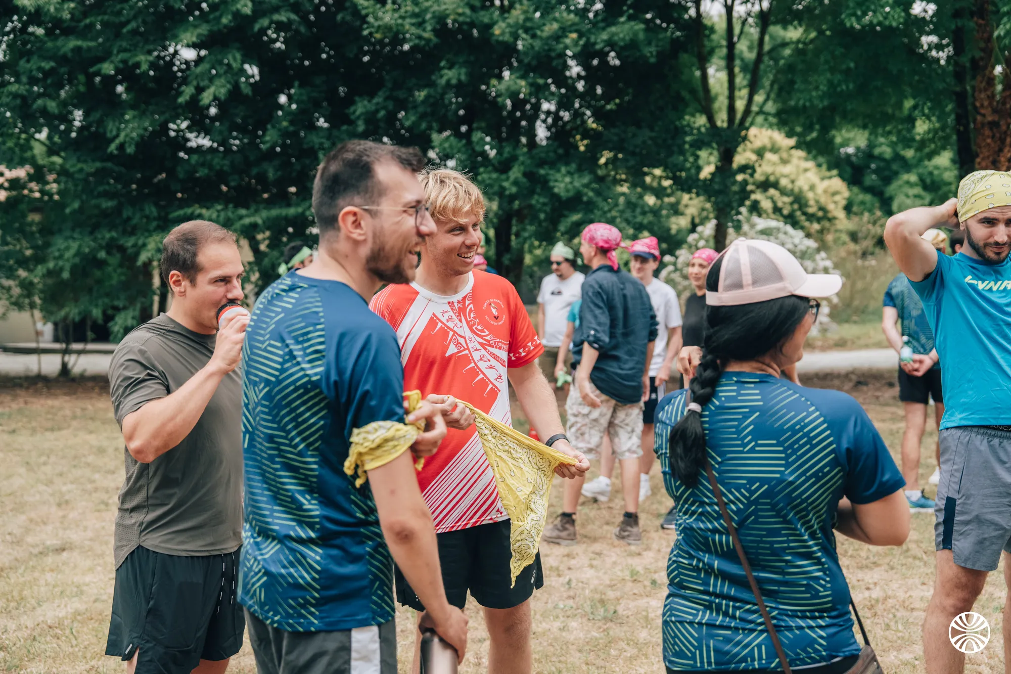 Groupe de personnes en tenue décontractée discutant dans un parc avec des arbres en arrière-plan.