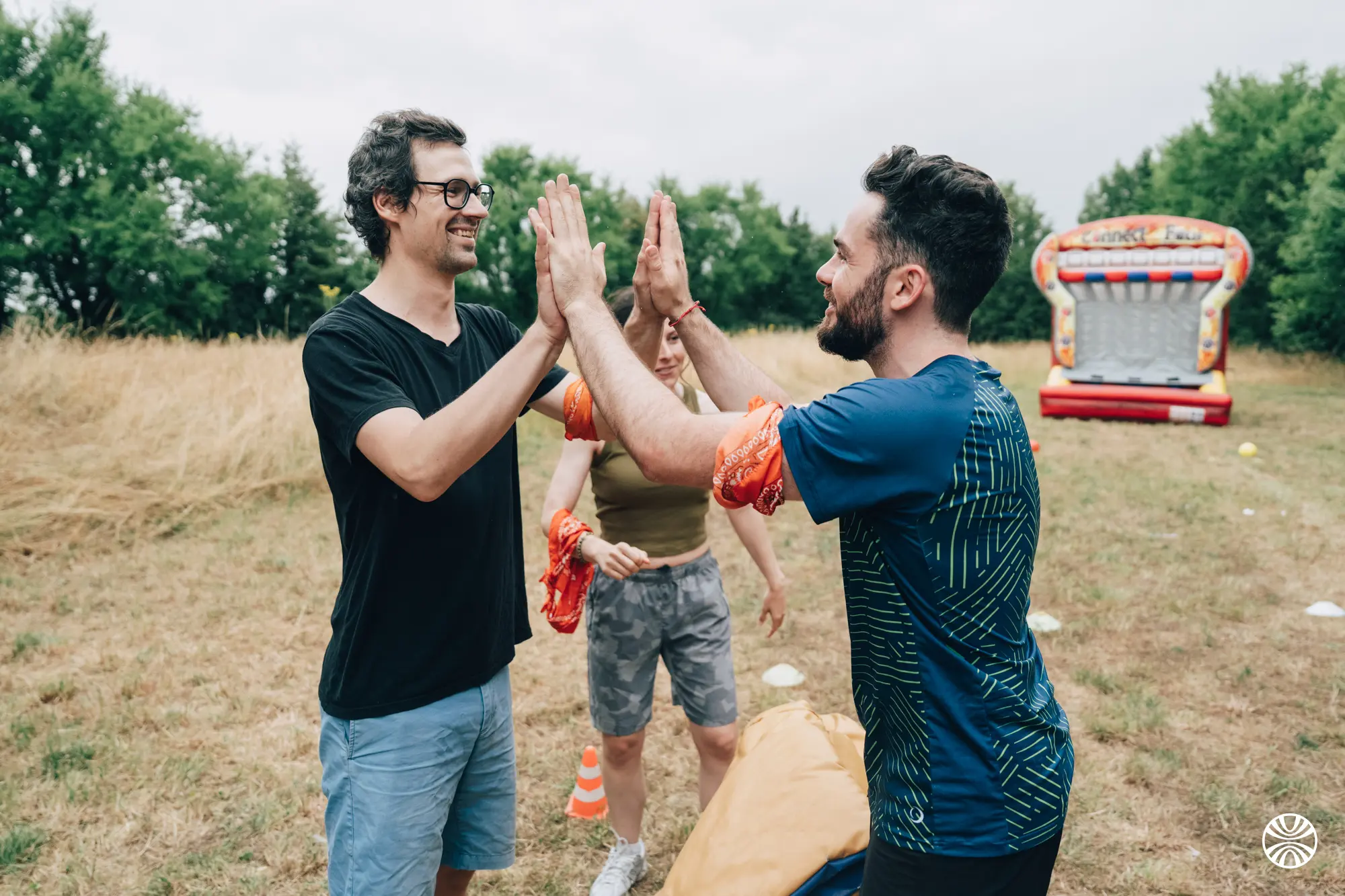 Groupe de personnes participant à un jeu en plein air, une personne au premier plan lançant un sac jaune.