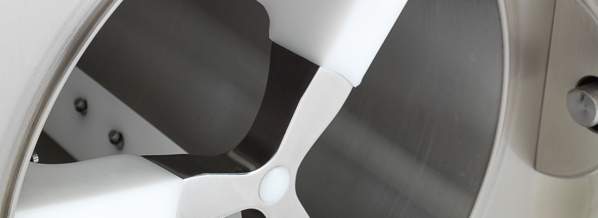 Nahaufnahme eines metallischen Mischers oder Rührwerks in einem zylindrischen Behälter.