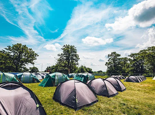Multicoloured tents placed in open green field