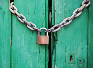 a padlock holding closed a chain in front of a green wooden door