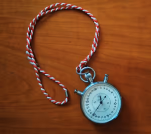 a stopwatch on a red and white string on a wood background