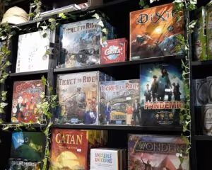 A shelf of board games including family board games Dixit, Ticket to Ride Europe, Pandemic, and Catan
