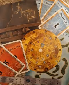game components for the game exit the forgotten island, showing game booklet, riddle cards, answer cards, decoder disk, and island map page