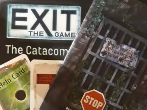 The escape room board game Exit, showing blue answer cards, orange riddle cards and green hint cards, as well as a code wheel and a folded poster