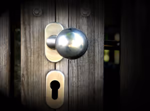 a wooden door with a silvery brass doorknob and keyhole slightly ajar