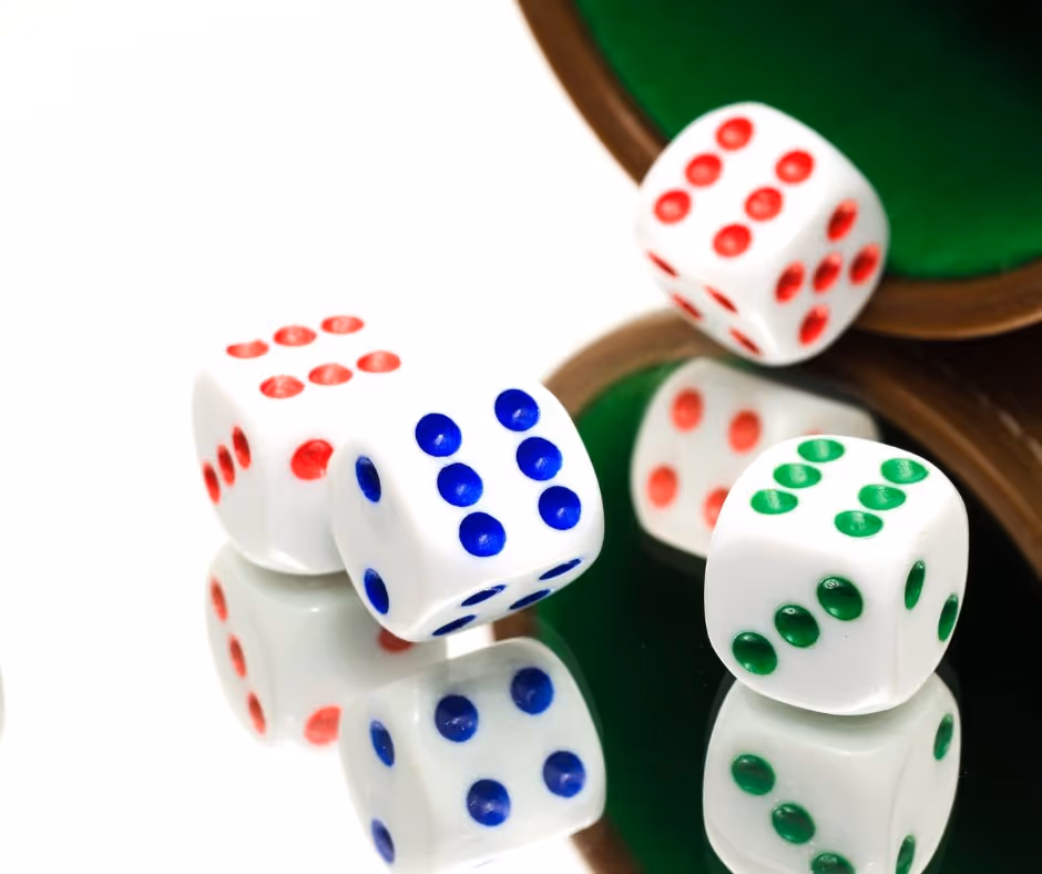 Four white dice with coloured dots being rolled onto a mirrored surface as part of a board game