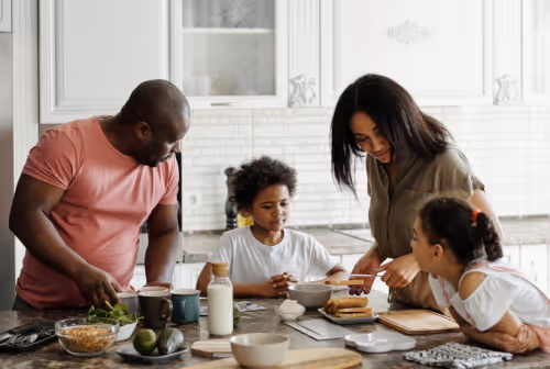 a family with two parents and two children around a table with cooking ingredients