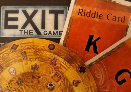the box of an exit game, showing two orange riddle cards and a golden card decoder disk