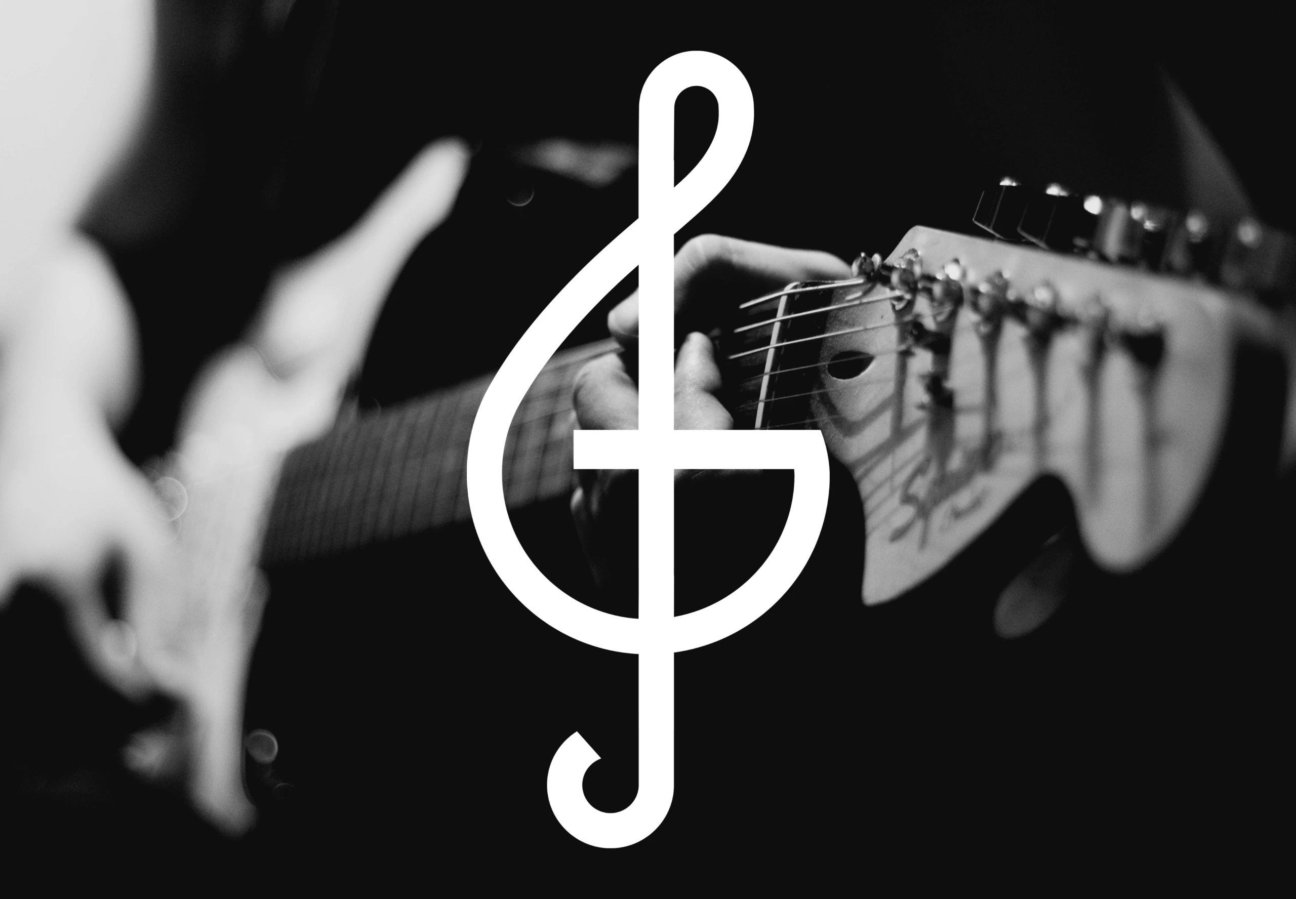 Gros plan en noir et blanc d'une clé de sol blanche superposée sur les mains d'un musicien jouant de la guitare