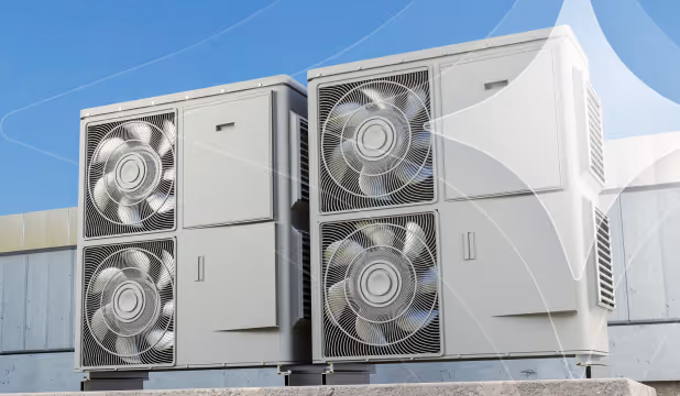 Two large outdoor air conditioning units with visible fans installed on a rooftop against a clear blue sky.